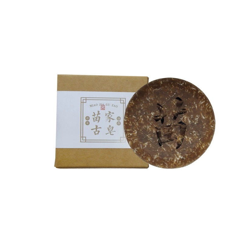 A photo of a Miao - family ancient soap and its packaging box. The soap has Chinese characters on it, and the box is labeled "Miao Gu Zao" in Chinese.