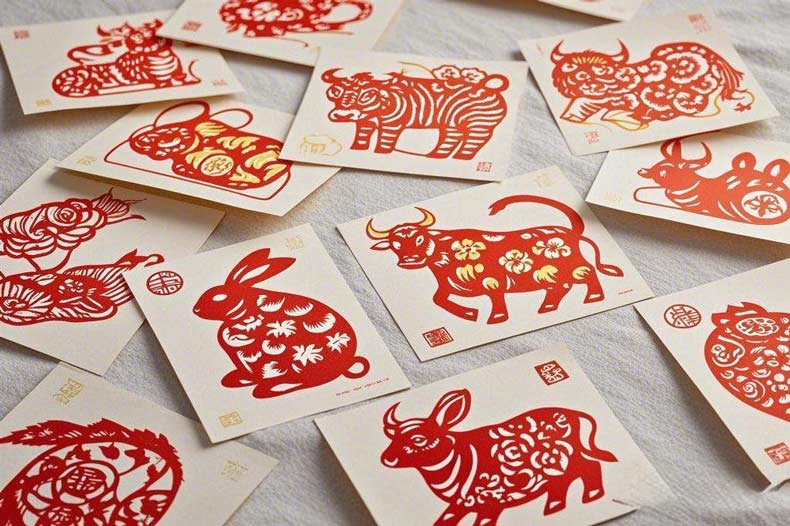 A collection of red Chinese zodiac paper - cuttings including rat, ox, rabbit and other animals on light - colored backgrounds.