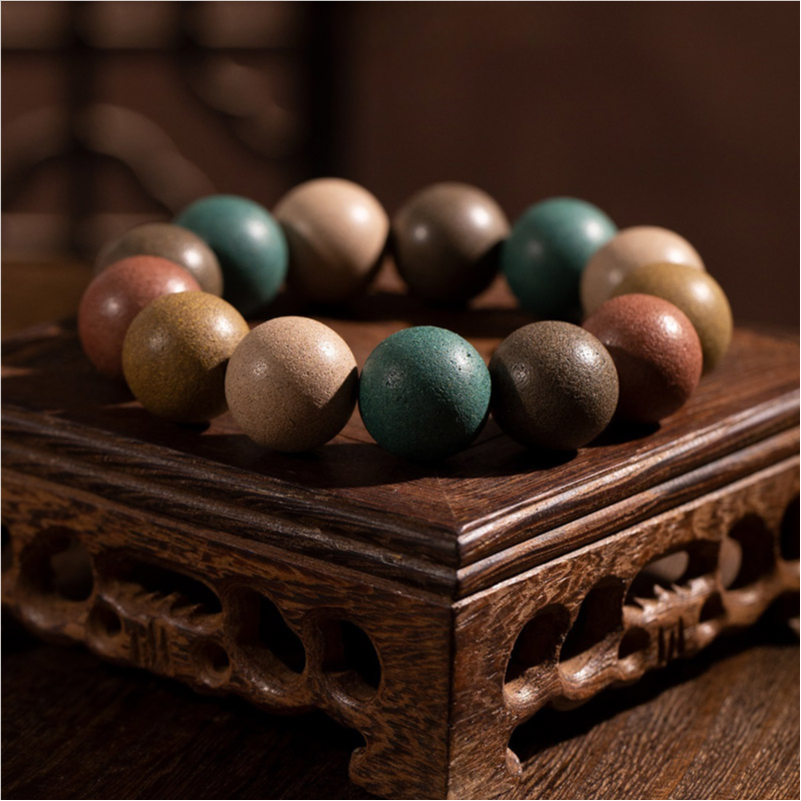 A Chinese Five - Elements Herbal Incense Bead Bracelet is placed on an intricately - carved wooden base, showcasing the multi - colored beads inspired by traditional Chinese medicine and Five - Elements theory.